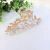 Piranha de metal dourado com flores brancas e pedras de strass grandes. Ideal para penteados sofisticados e eventos especiais. Pistache Acessórios.