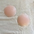 Protetores de mamilos de silicone em embalagem, com dois discos em tom rosa claro.