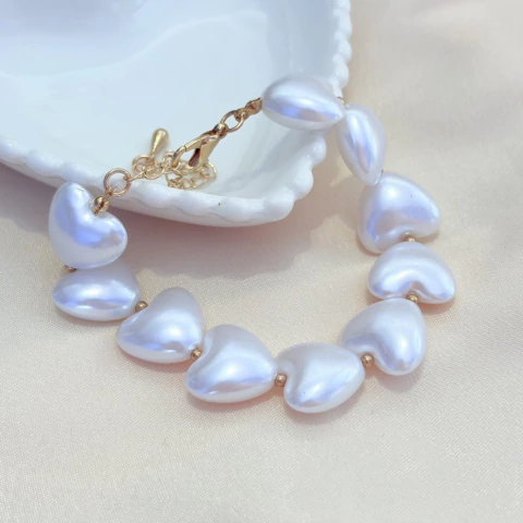 Pulseira de corações de pérola com fecho dourado e ajuste, delicada e versátil para todos os estilos.