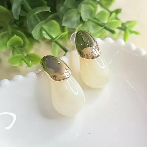 Brinco de gota moderno com acabamento em acrílico branco mesclado e detalhes em metal dourado. Ideal para quem busca estilo e sofisticação com leveza.

