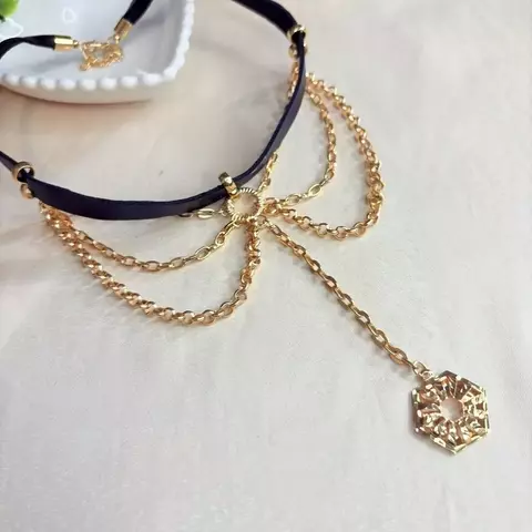 Choker de courino com correntes douradas e pingente hexagonal. Acessório moderno em bijuteria fina, ideal para looks urbanos e estilosos.