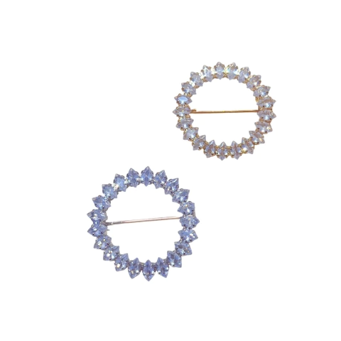 Broche redondo com pedras de zircônia brilhantes e abertura central. Disponível em base dourada ou prateada, com fecho de alfinete.