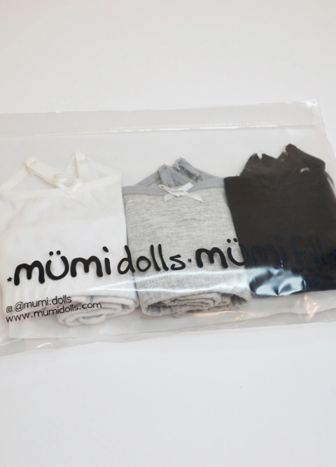 Pack de tres tops básicos para niña en colores blanco, gris y negro, presentados en bolsa transparente con logo de Mümi Dolls