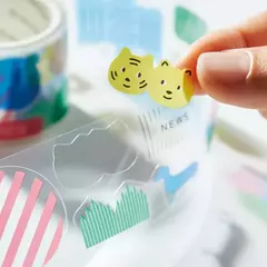 Mano sosteniendo un sticker transparente con diseño de dos caras de gato amarillas de un rollo de stickers PET