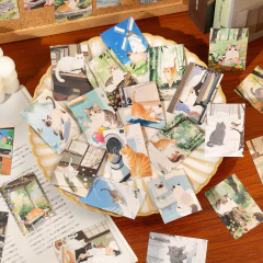 Mini block de stickers de papel con ilustraciones de gatos en diferentes escenas y fondos naturales y domésticos.