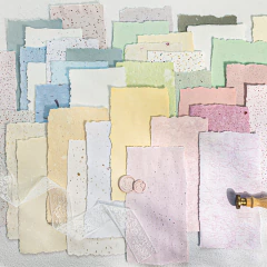 Hojas de papeles especiales de colores pastel con texturas y bordes irregulares, dispuestas en capas sobre una superficie clara