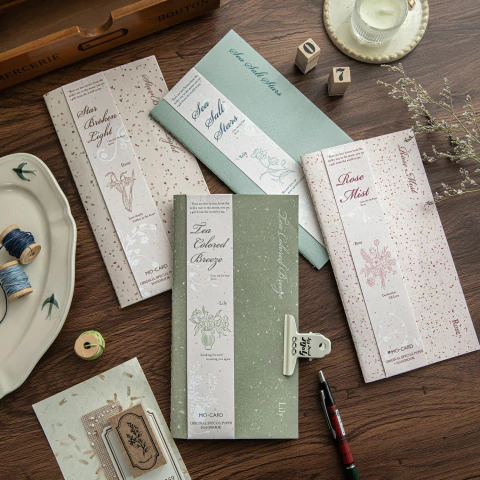 Libretas papeles especiales Colorful Ink con colores suaves sobre mesa de madera, acompañadas de accesorios de escritorio