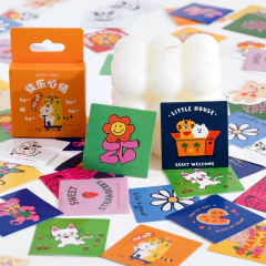 Una variedad de stickers de papel coloridos y divertidos, incluyendo un diseño de flor sonriente y otros dibujos animados, junto a una caja que los contiene.