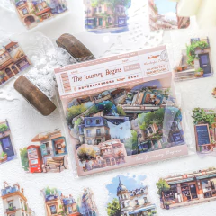 Pack de 30 stickers con ilustraciones de edificios y escenas urbanas estilo acuarela, presentados en un empaque transparente con diseño de ticket de viaje.