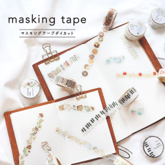 Rollos de washi tape troquelada con diseños variados sobre cuadernos abiertos, mostrando patrones de flores, notas musicales y objetos decorativos
