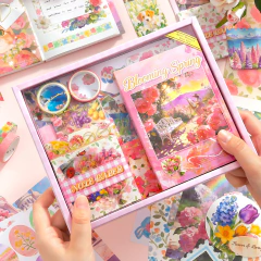 Manos sostentiendo una caja rosa con Set de journaling Blooming Spring  Simno con cuaderno A6, cintas adhesivas decorativas y papeles para scrapbooking.
