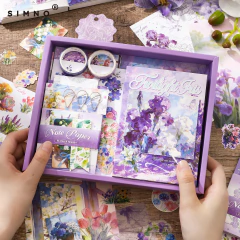 Set de journaling Iris Twilight Iris con cuaderno A6, cintas washi decorativas y papeles para scrapbooking ilustrados con flores en caja violeta.