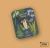 Pin metálico con diseño de hongos marrones sobre tarjeta decorativa con ilustraciones de plantas y flores, colección Fungi de Ediciones de la Montaña