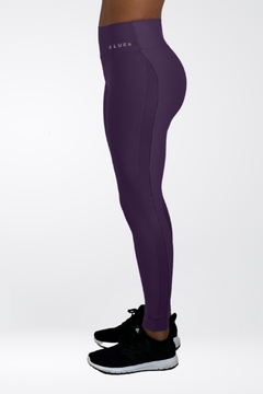 Calça legging roxa da marca Lurk, vista de lado, combinada com tênis pretos.