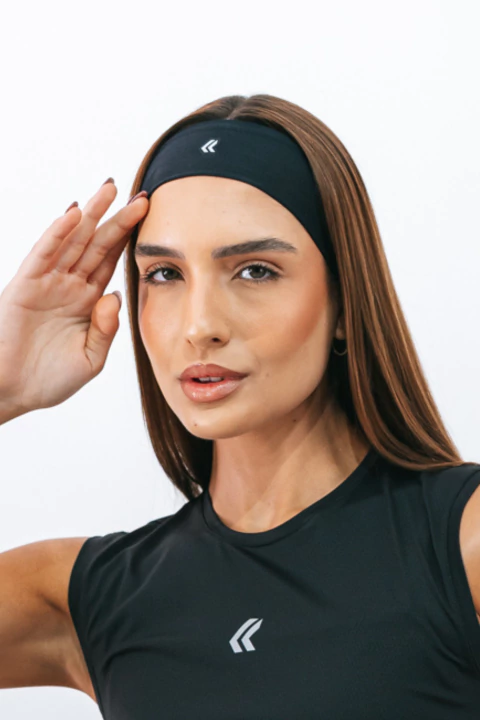 Mulher usando uma faixa de cabelo preta da marca Lurk, com expressão confiante e um braço levantado.