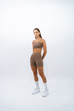 Modelo vestindo top slim marrone da Lurk, com calças curtas e tênis brancos, em fundo branco.