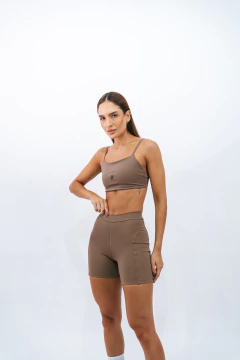 Mulher usando shorts slim marrone da marca Lurk, com parte superior em tom semelhante, em um fundo branco.