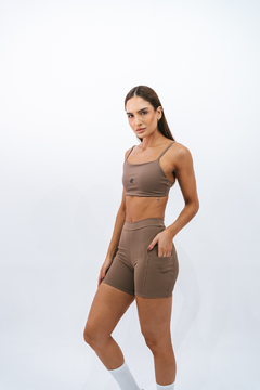 Modelo usando shorts slim marrone da marca Lurk, com top combinando, em fundo branco.
