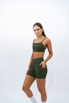 Modelo usando shorts slim verde e top, ideal para atividades esportivas.