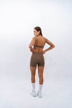 Modelo feminina usando top slim marrone da Lurk, de costas, com shorts marrons e meias brancas.