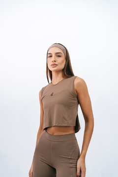 Modelo feminina vestindo uma regata cropped marrone da marca Lurk, com detalhe no logo na parte frontal.