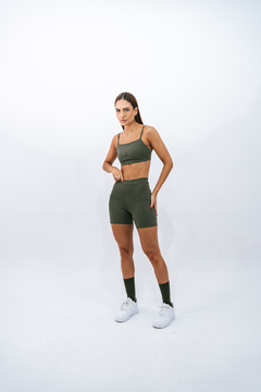Modelo usando shorts slim verde musgo e top combinando, ideal para atividades esportivas.