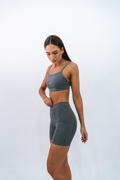 Modelo vestindo um top slim cinza com alças finas e short curto, destacando a roupa esportiva feminina.