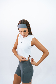 Modelo feminina vestindo regata cropped branca da Lurk, ajustando o modelo enquanto usa shorts cinza.