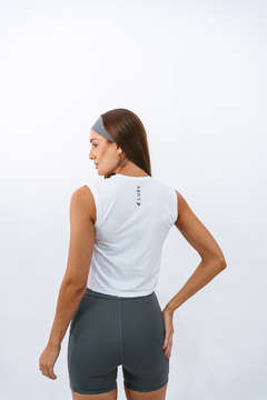 Regata cropped branca Lurk vista de trás, modelo feminino com faixa de cabelo cinza.