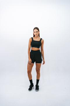 Modelo usando top preto Lurk e shorts preto em fundo branco.