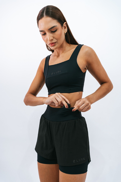 Mulher vestindo shorts Core Preto da Lurk, ajustando a roupa antes de uma atividade esportiva.
