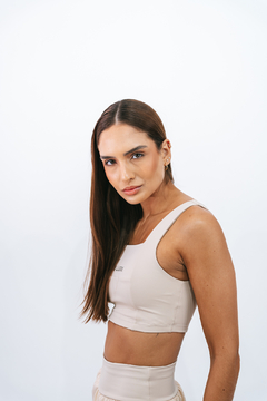 Modelo feminina usando o top Core Duna Lurk em cor bege, com olhar confiante e cabelo liso.