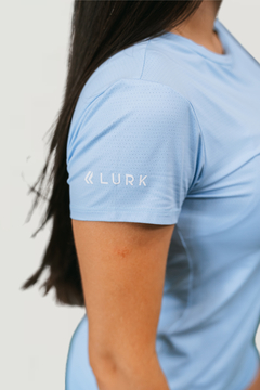 Camiseta feminina Dry Poliamida na cor azul, com o logo LURK na manga.