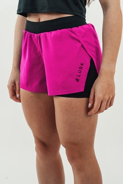 Shorts feminino 2 em 1 na cor pink, com detalhe em preto, exibindo a logo da marca Lurk.