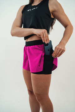 Modelo usando shorts feminino 2 em 1 na cor pink, com um bolso lateral para celular.