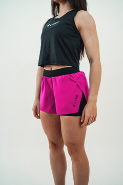 Shorts feminino 2 em 1 na cor pink, modelo Lurk, com detalhe em preto, exibido em uma modelo.