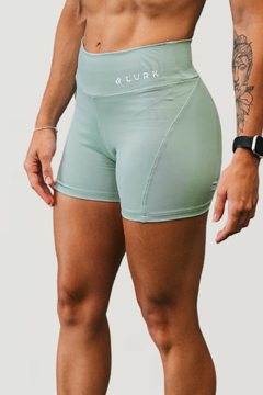 Shorts femininos em tom verde claro, com a marca LURK, ideal para atividades esportivas.