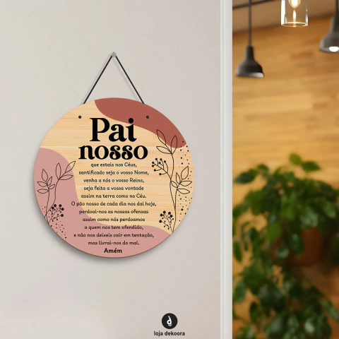 Enfeite redondo em MDF com a Oração Pai Nosso, decorado com elementos florais e cores suaves, pendurado na parede.