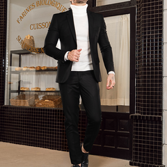 Hombre vestido con un traje slim fit negro, camisa de cuello alto blanca, caminando en una panadería.
