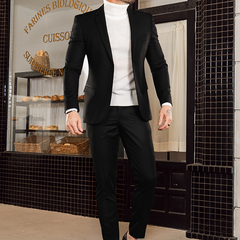 Hombre vestido con un traje negro slim fit, combinando con un suéter blanco, en un entorno elegante.