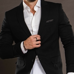 Hombre vistiendo un blazer premium slim fit negro con camisa blanca, ajustando su prenda.