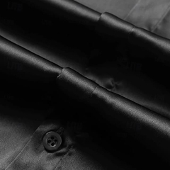 Primer plano de una camisa de satín negra, mostrando el detalle del cuello y un botón.