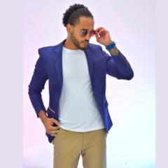 Hombre posando con un blazer slim fit azul oscuro y gafas de sol, sobre un fondo suave.