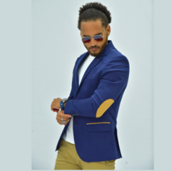 Hombre usando un blazer slim fit azul oscuro con coderas marrones, posando con gafas de sol.