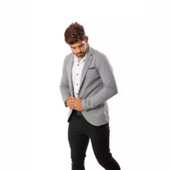 Hombre vistiendo un blazer sport slim fit gris con camisa blanca y pantalones oscuros, ajustándose la chaqueta.