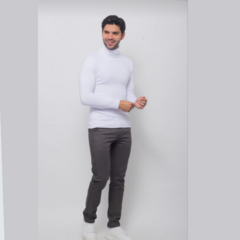 Modelo vistiendo un buzo cuello tortuga blanco, con pantalones oscuros y zapatillas blancas.