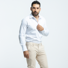 Hombre posando con una camisa blanca de ajuste slim fit y pantalones beige.