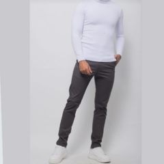 Buzo de cuello tortuga blanco, usado por un modelo con pantalones oscuros y zapatillas blancas.