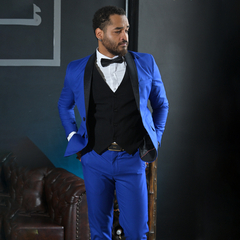Hombre elegante con traje azul y chaleco negro, posando con una expresión seria.