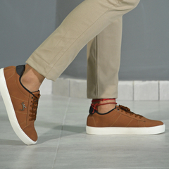 Zapato casual Siena, color marrón, siendo usado con pantalones claros en un entorno moderno.